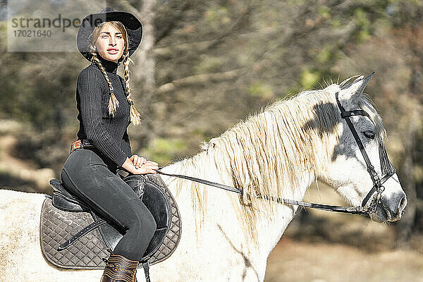 Porträt einer Frau beim Reiten auf einer Pferdekoppel