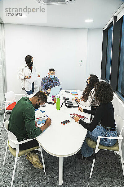 Kreative männliche und weibliche Kollegen diskutieren  während sie im Sitzungssaal im Büro sitzen