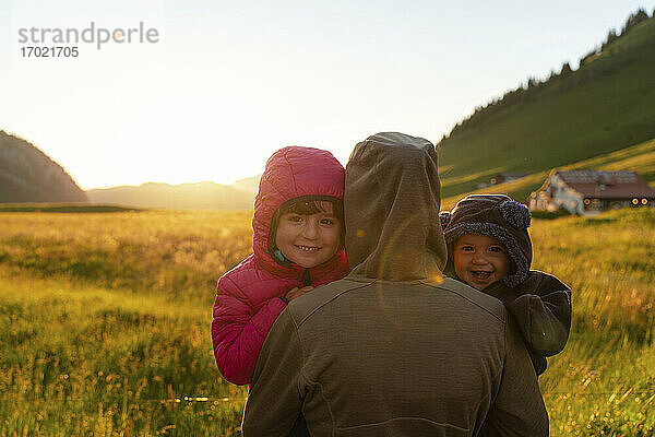 Lächelnde Kinder mit ihrer Mutter bei Sonnenuntergang in den Ferien am Col Des Aravis  Haute-Savoie  Frankreich