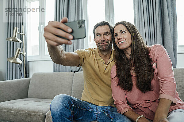 Lächelndes reifes Paar nimmt Selfie in Wohnung