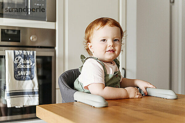 Porträt eines kleinen Mädchens  das am Küchentisch sitzt
