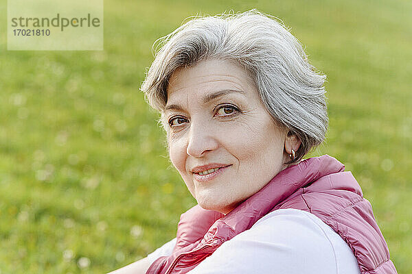 Lächelnde reife Frau mit grauem Haar in einem öffentlichen Park