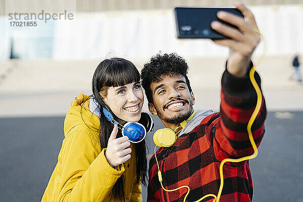 Junger Mann nimmt Selfie durch Handy mit weiblichen Freund  während im Freien stehen
