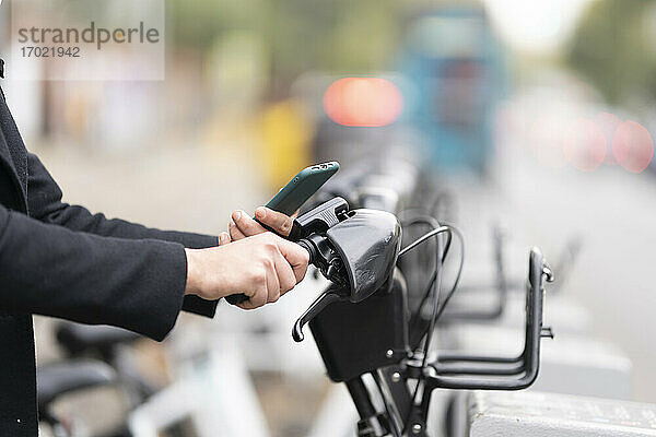 Mann entriegelt elektrisches Sharing-Fahrrad in der Stadt per Smartphone