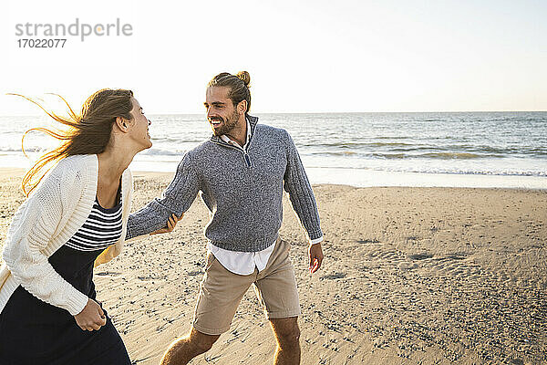 Fröhliches junges Paar  das sich an einem sonnigen Tag am Strand vergnügt