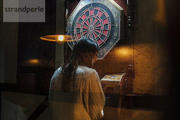 Junge Frau spielt Darts in einer Bar