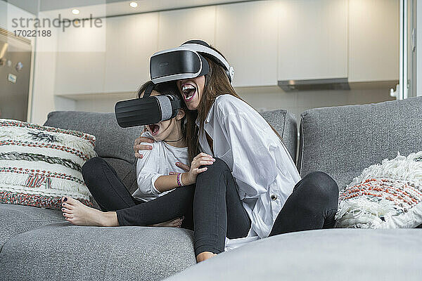 Aufgeregte Mutter und Tochter verwenden Virtual-Reality-Brille zu Hause