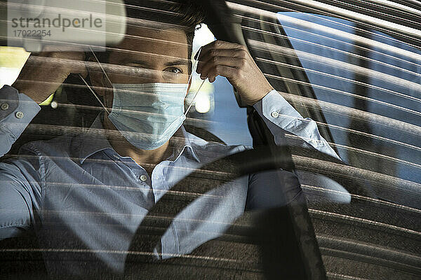 Geschäftsmann mit Gesichtsschutzmaske im Auto während COVID-19