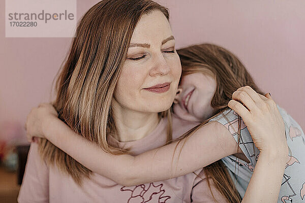 Tochter umarmt Mutter an der Wand zu Hause