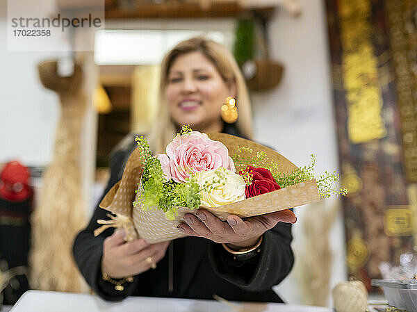 Floristin hält Blumenstrauß im Blumenladen