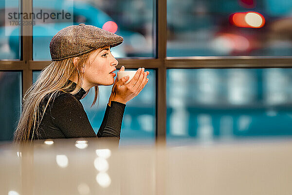 Frau trinkt Kaffee  während sie nachts in einem Cafe sitzt