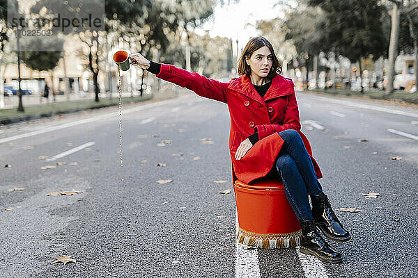 Junge Frau mit Einstellung verschüttet Kaffee aus einer Tasse auf der Straße