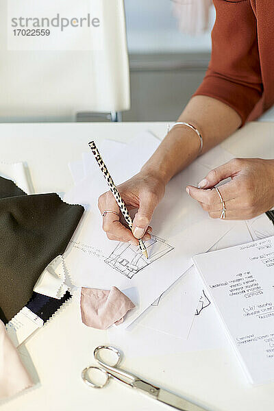 Weibliche Designerin zeichnet auf Papier am Schreibtisch im Atelier