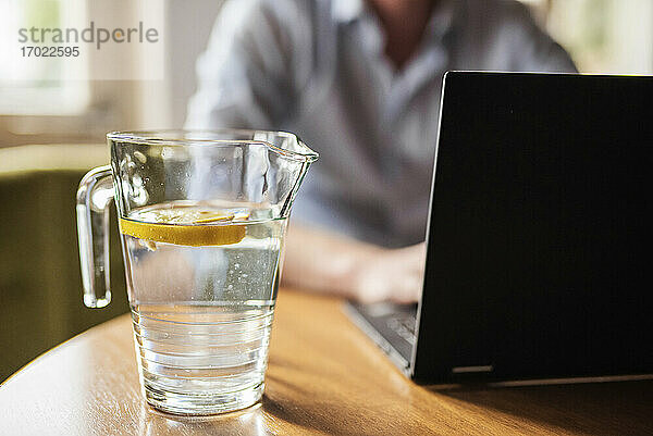 Männlicher Unternehmer arbeitet über einem Laptop auf einem Tisch zu Hause