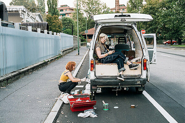Junge Frauen arbeiten an einem Lieferwagen