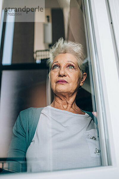 Blick auf eine ältere Frau durch ein Fenster
