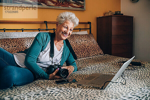 Fotograf telefoniert zu Hause mit seinem Laptop