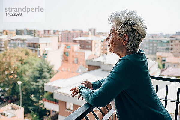 Frau auf dem Balkon ihrer Wohnung