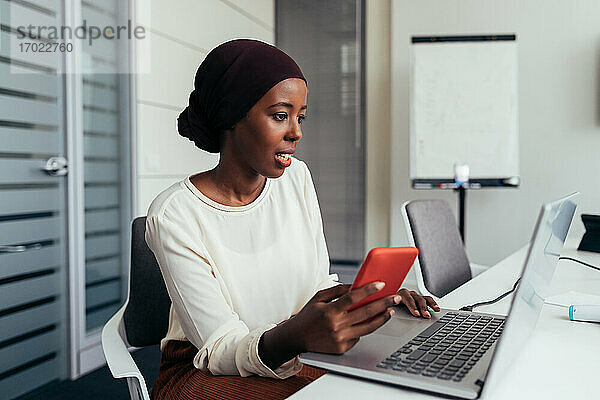 Geschäftsfrau mit Smartphone und Laptop