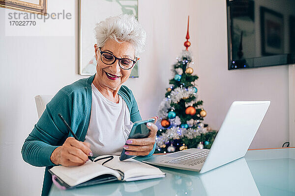 Frau arbeitet zu Hause  Weihnachtsbaum im Hintergrund