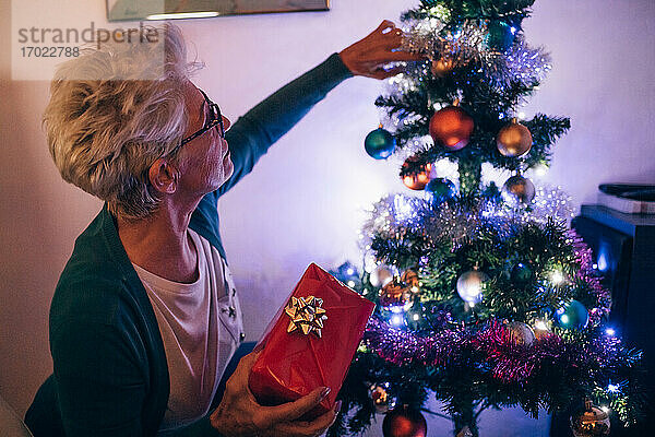 Frau beim Schmücken des Weihnachtsbaums