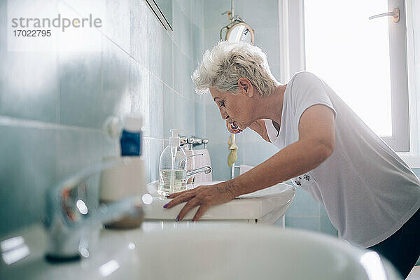 Frau putzt sich im Badezimmer die Zähne