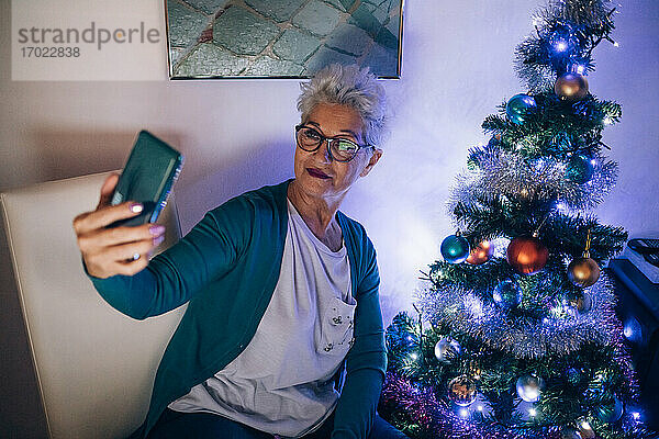 Frau führt Videoanruf am Weihnachtsbaum