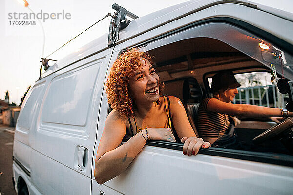 Glückliche junge Frau lehnt sich aus dem Fenster eines Lieferwagens