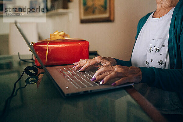 Frau mit Laptop und Weihnachtssachen Freigegeben (PR)esent neben ihr