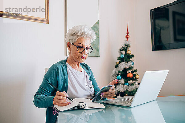 Frau arbeitet von zu Hause aus  Weihnachtsbaum im Hintergrund