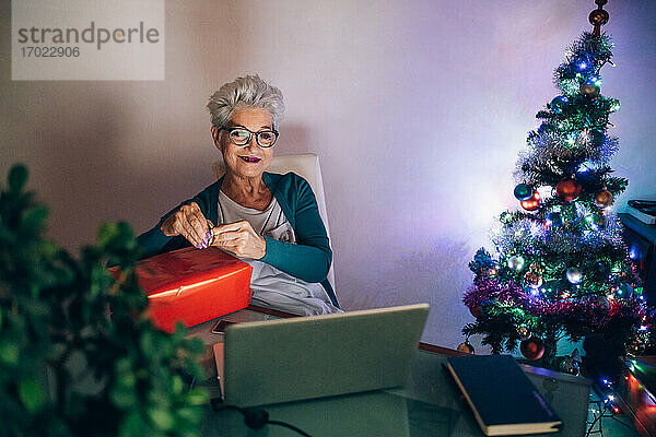 Frau bei Videoanruf mit Weihnachtsgeschenk