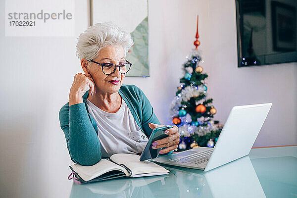 Frau arbeitet zu Hause  Weihnachtsbaum im Hintergrund