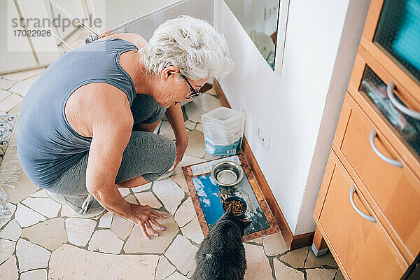 Frau gibt ihrer Katze Futter