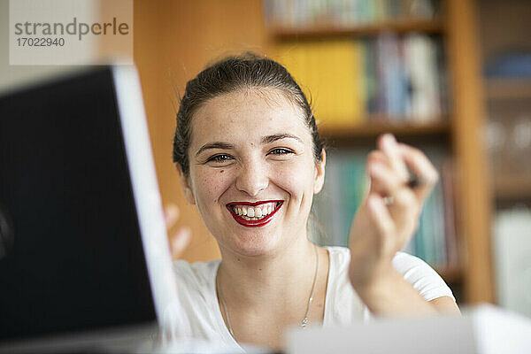 Junge Frau am Computer in der Bibliothek  lächelnd