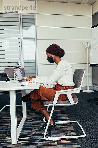 Geschäftsfrau mit Gesichtsmaske  die im Büro arbeitet
