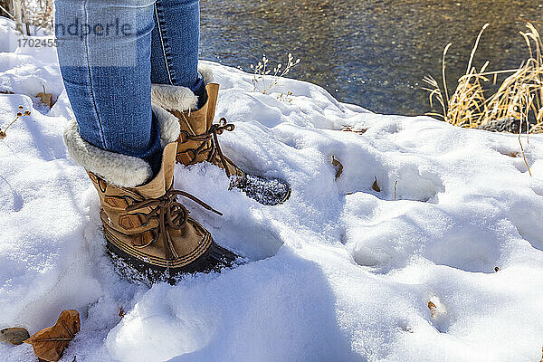 Beine einer älteren Frau in Wanderschuhen im Schnee stehend