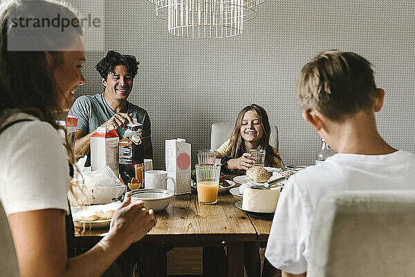 Glückliche Familie mit Frühstück auf Esstisch zu Hause