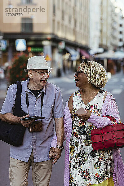 Glückliches älteres Paar hält Hände in der Stadt spazieren
