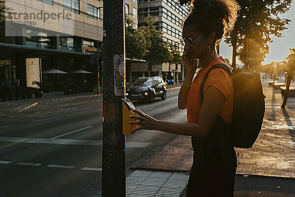 Seitenansicht der Geschäftsfrau Drücken der Taste auf dem Gehweg beim Überqueren der Straße in der Stadt