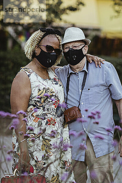 Heterosexuelles Paar mit Arm um stehend im Park während der Pandemie