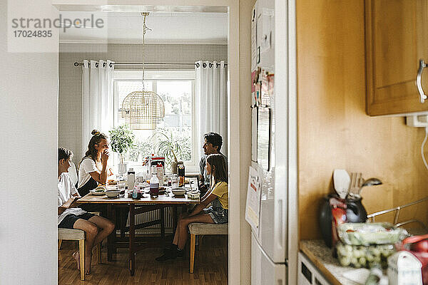 Glückliche Familie beim Frühstück durch die Türöffnung der Küche zu Hause gesehen