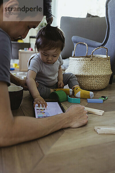 Baby Sohn Blick in digitale Tablette sitzen mit Vater im Wohnzimmer