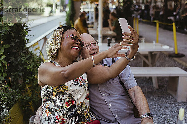 Fröhliches heterosexuelles Paar nimmt Selfie auf Smartphone im Café