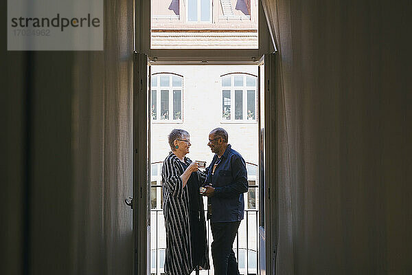 Älteres Paar mit Kaffeetasse bei der Freizeitgestaltung auf dem heimischen Balkon
