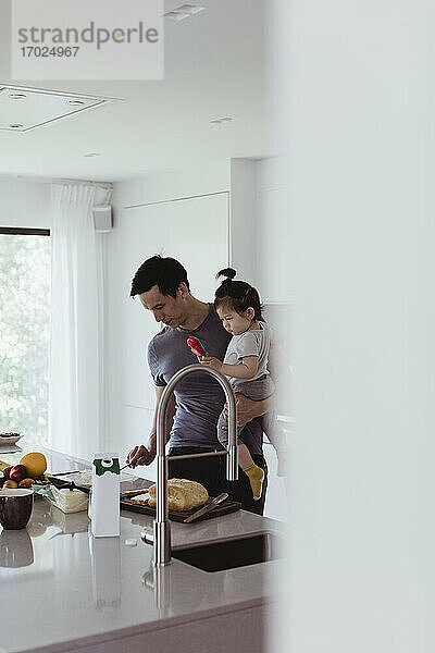 Vater trägt männliches Kleinkind bei der Zubereitung von Essen in der Küche