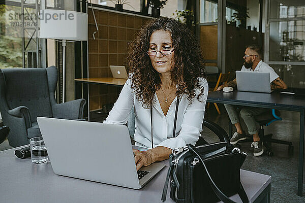 Reife Geschäftsfrau arbeitet am Laptop  während sie in einer neuen Firma sitzt