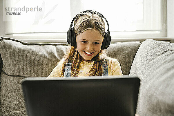 Lächelndes Mädchen studiert auf Laptop zu Hause