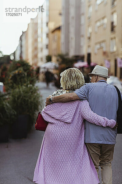 Rückansicht eines älteren Paares mit Arm um Spaziergang in der Stadt