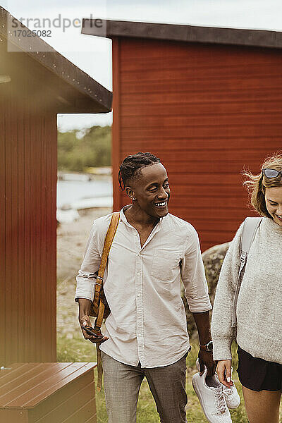 Lächelnde Freunde zu Fuß gegen Hütte im Urlaub