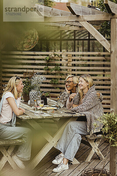 Weibliche Freunde verbringen Zeit mit Großmutter am Tisch im Hinterhof